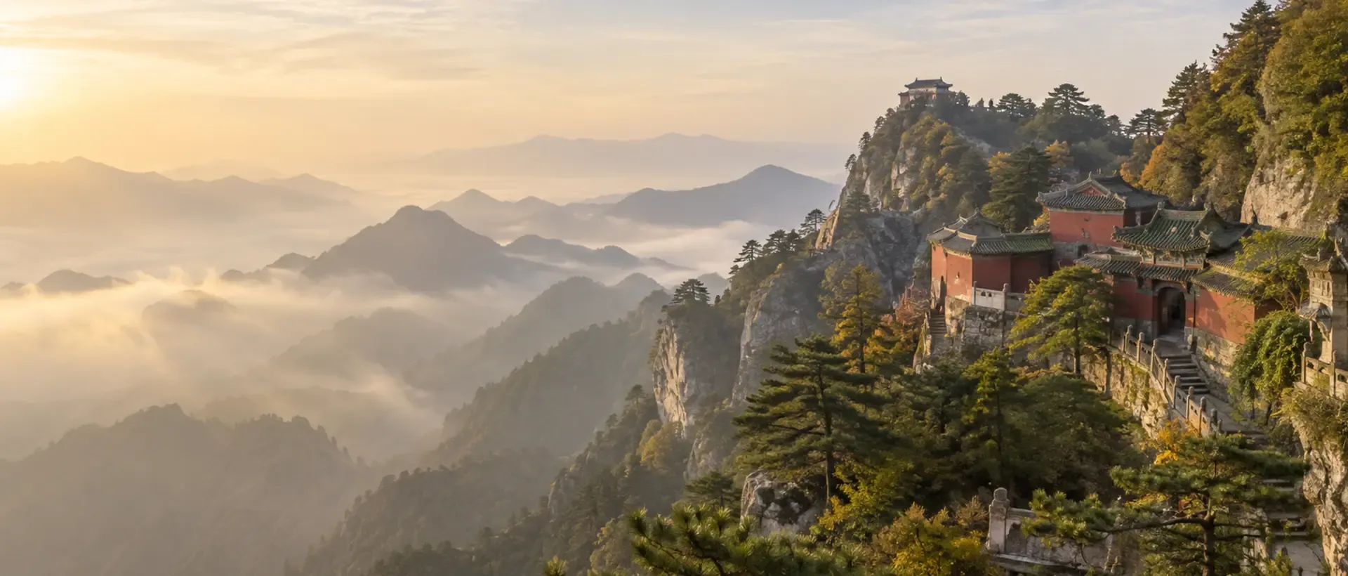Historic Wudang temples rise above pine-covered mountain ridges in warm morning light.
